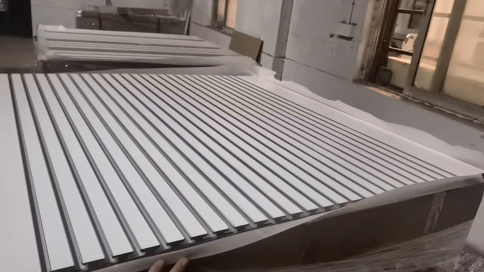 Close view of a stacked custom MDF slatwall panel batch showing repeated insert spacing