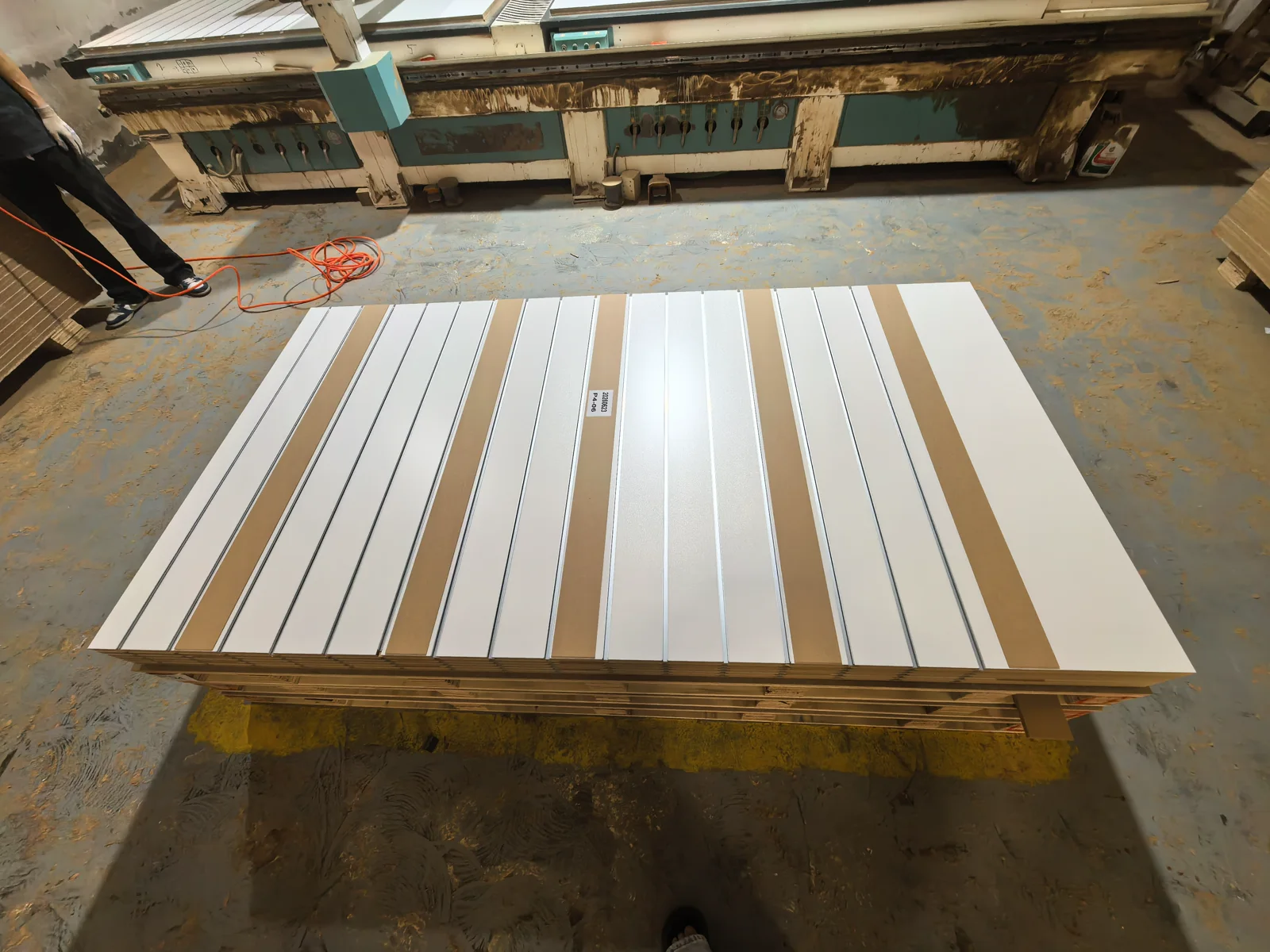White MDF slatwall panels with mixed groove spacing and metal inserts laid out in the YENC workshop